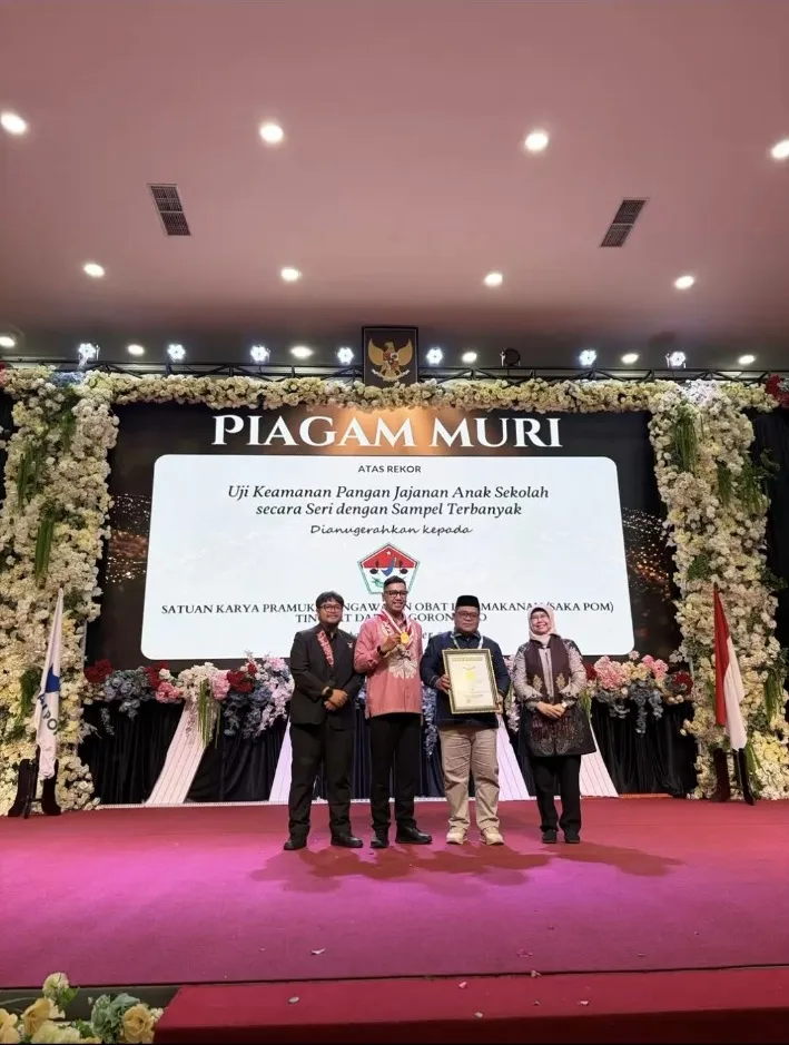 Foto penyerahan penghargaan dengan latar tulisan Piagam MURI.
